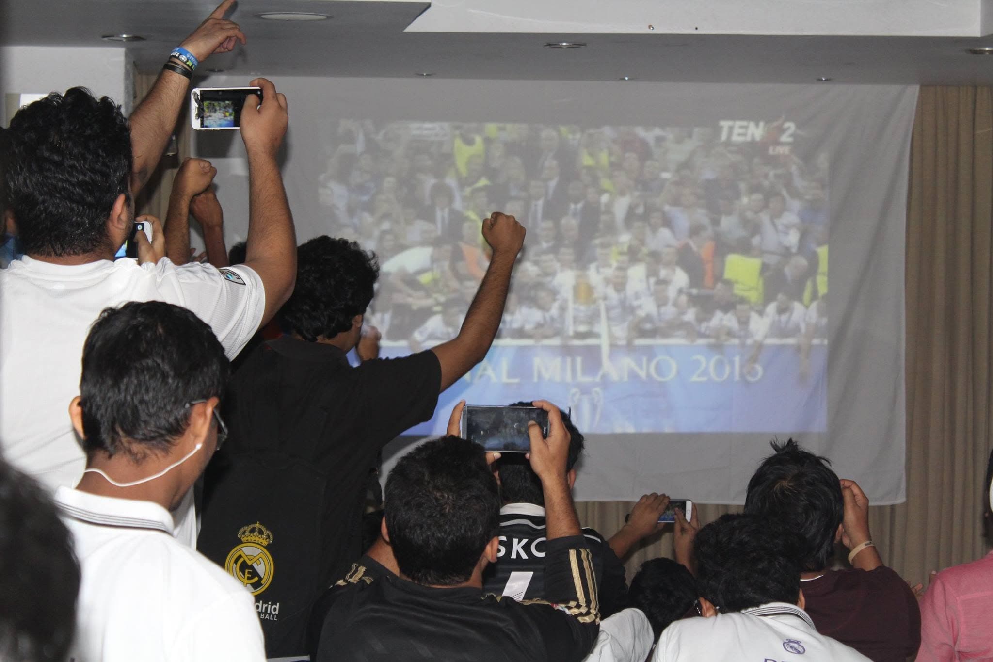 PMBD members celebrating and filming the trophy lift on screen during the 2016 Champions League final live screening in Milan, La Duodécima